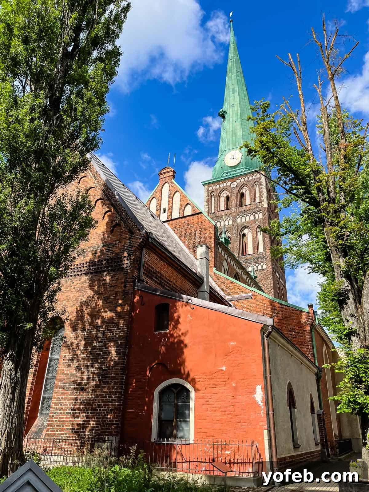 Unlock the Charm of the Baltics 3 Historic church with a distinctive copper steeple and red brick walls in a charming European setting.