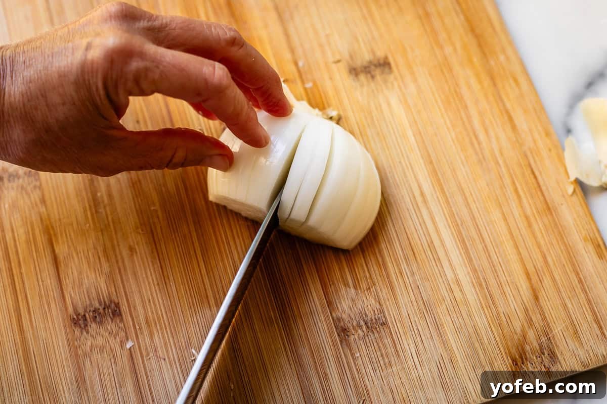 Chop Onions Like a Pro 14 Cutting vertical cuts off of root of an onion with a chef's knife on bamboo cutting board.