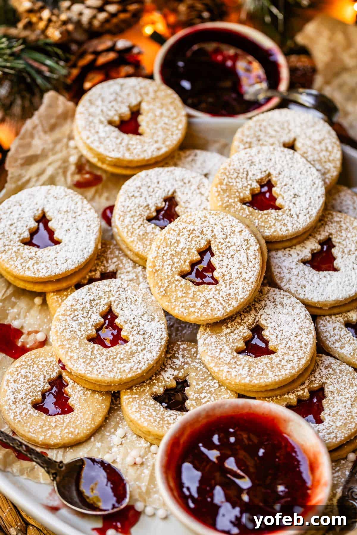 Melt-in-Your-Mouth Linzer Delights 21 A festive platter generously stacked with numerous Linzer cookies, accompanied by a small bowl of fresh raspberry jam, creating an inviting display.