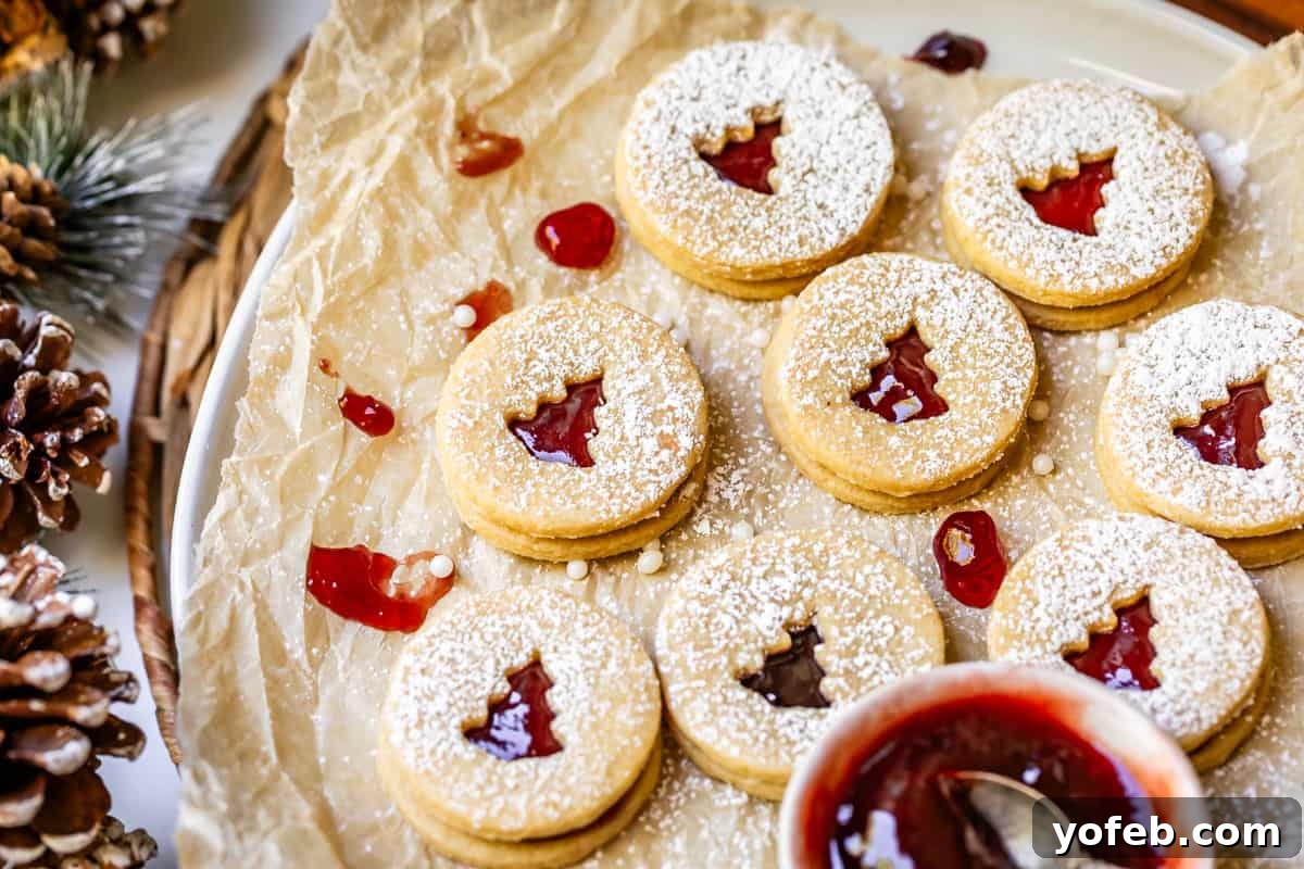 Melt-in-Your-Mouth Linzer Delights 4 A platter topped with a sheet of parchment paper, showcasing several unbaked Linzer cutout cookies ready for the oven.