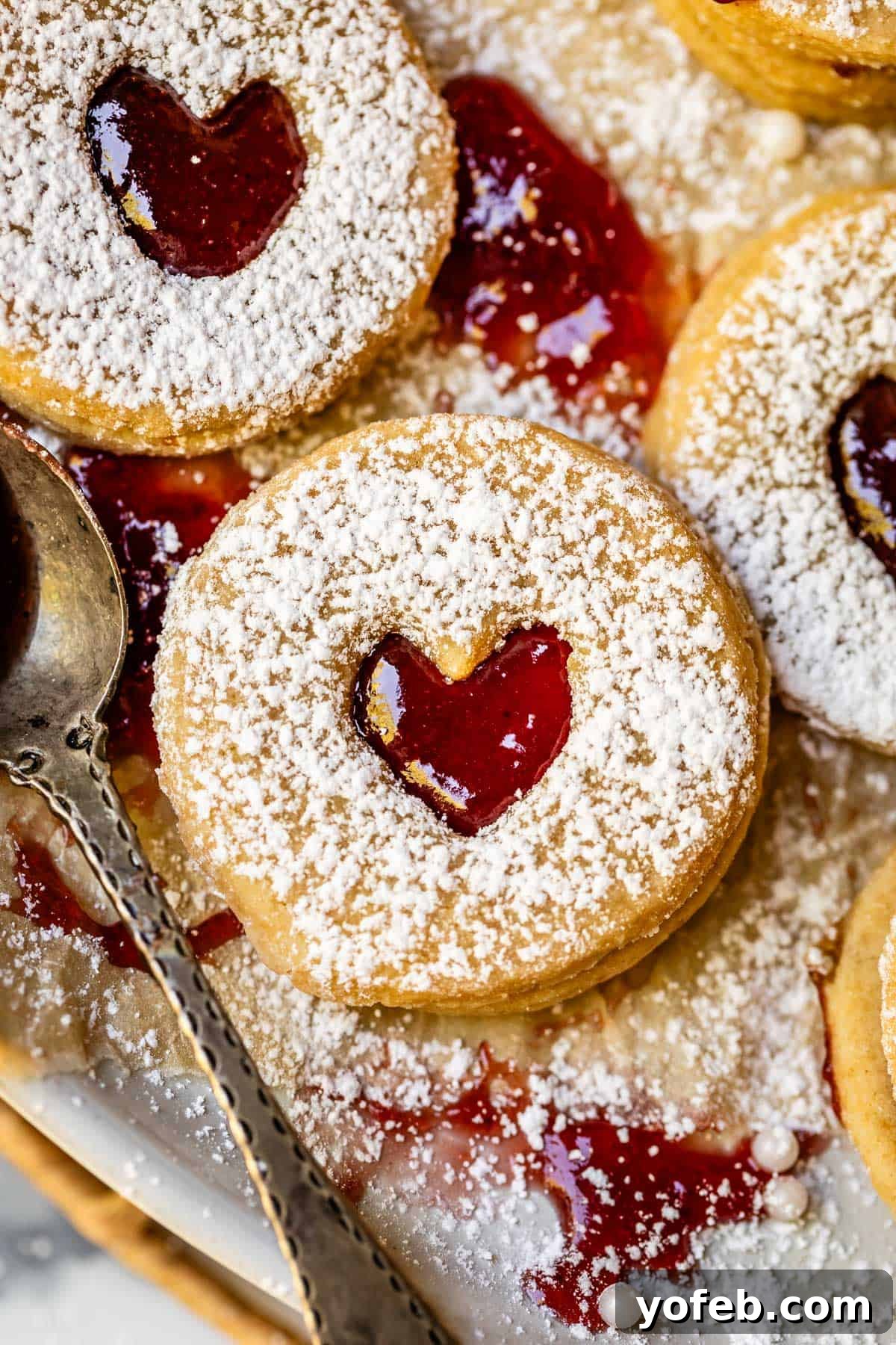 Melt-in-Your-Mouth Linzer Delights 6 Three perfectly dusted Linzer cookies, each featuring a charming heart cutout in the center, hinting at the sweet jam filling beneath.