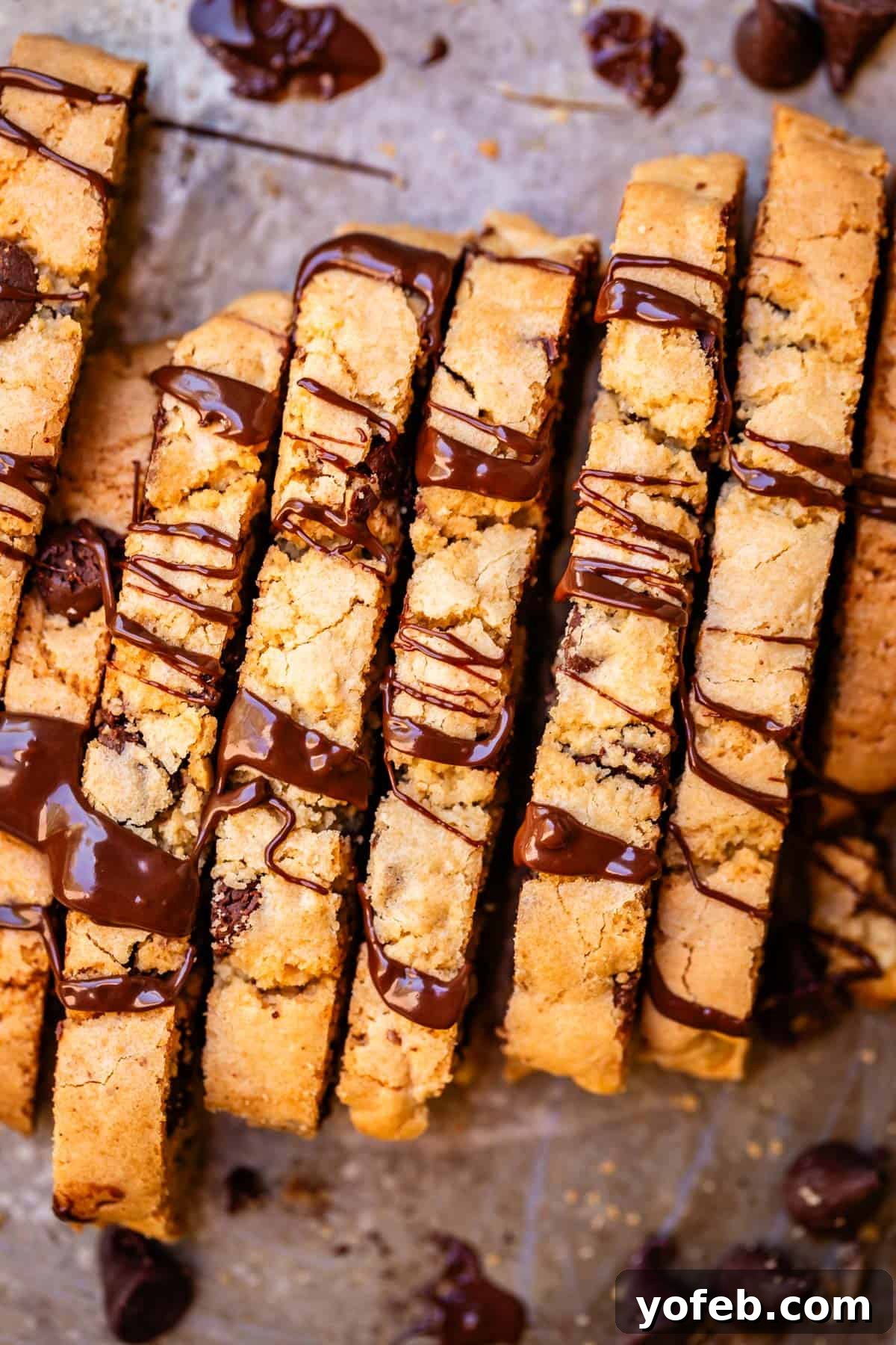 The Biscotti That Will Change Your Mind 3 A row of expertly baked biscotti, glistening with a delicate chocolate drizzle, arranged on a baking sheet.