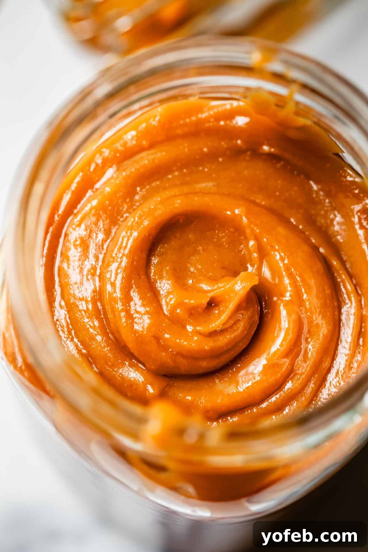 Dreamy Salted Caramel Sauce 10 A perfectly made and swirled, cooled salted caramel sauce nestled in a clear glass mason jar, showcasing its rich texture.