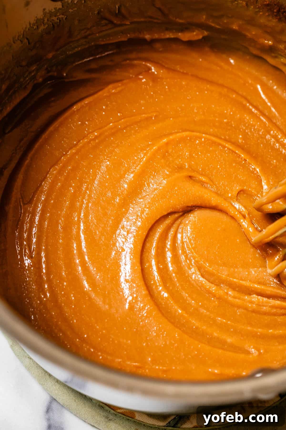 Dreamy Salted Caramel Sauce 11 A whisk vigorously stirs salted caramel sauce in a pot, demonstrating the rich, smooth consistency as it cooks.