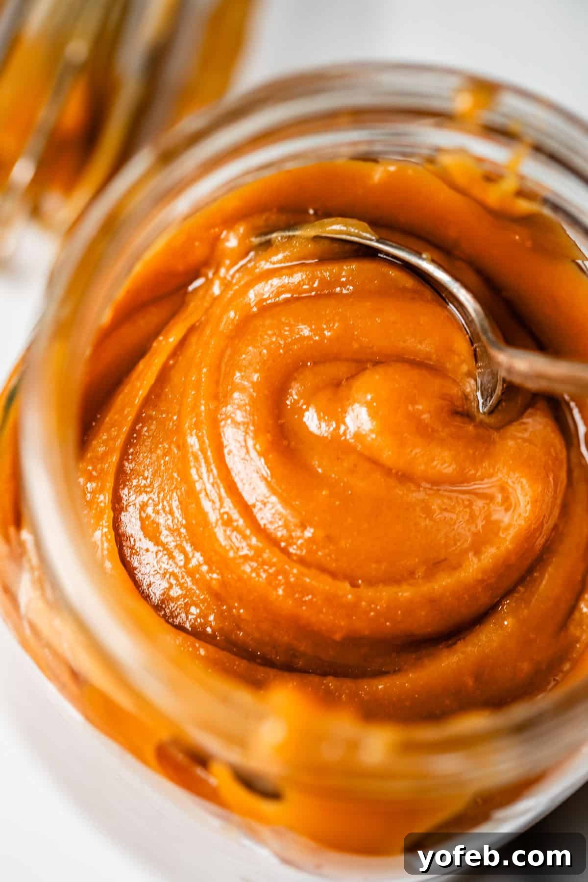 Dreamy Salted Caramel Sauce 25 A metal spoon eagerly digs into the rich, fudgy salted caramel sauce stored in a glass mason jar.