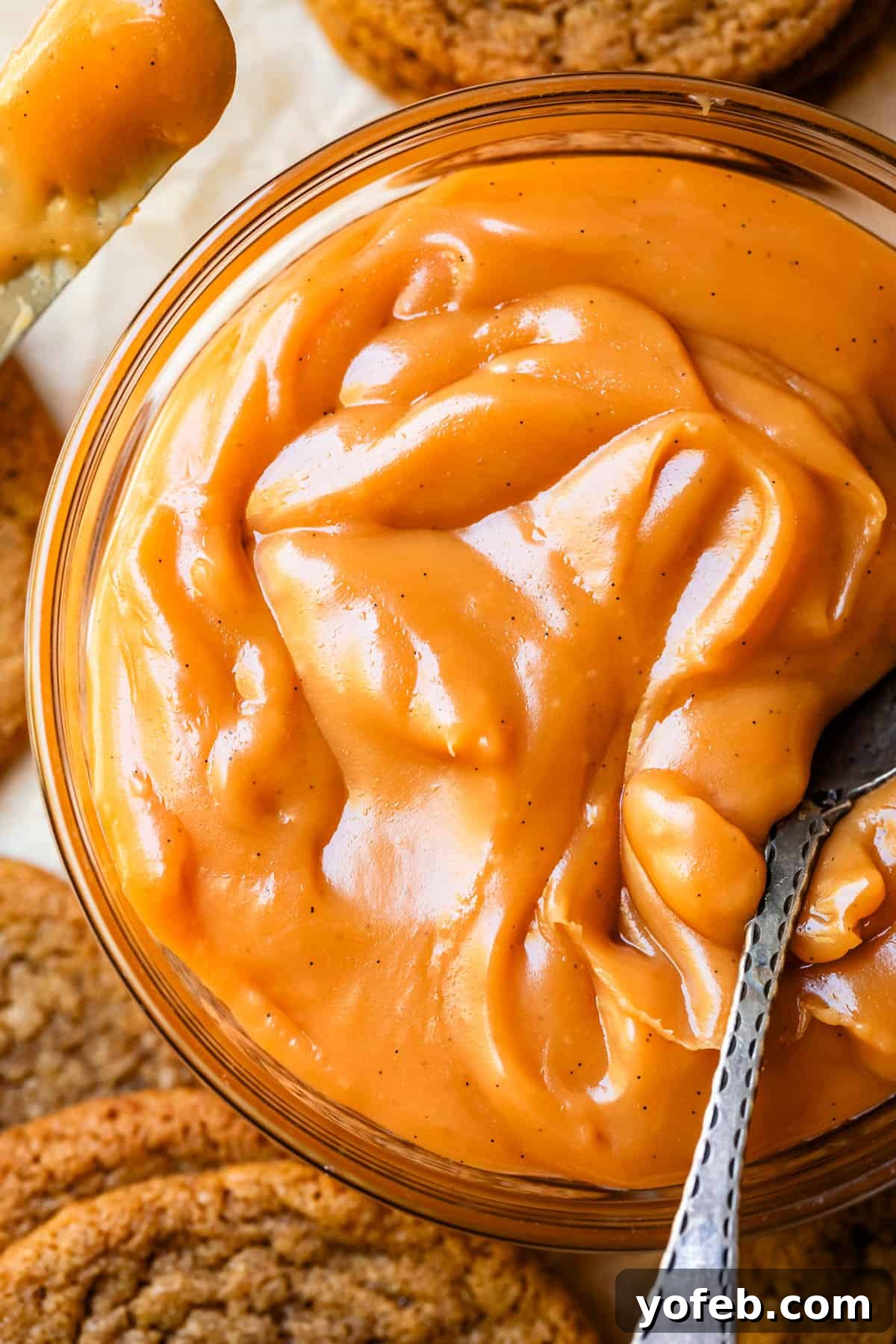 Dreamy Salted Caramel Sauce 8 A metal spoon rests inside a mason jar filled to the brim with smooth, rich salted caramel sauce, ready for indulgence.