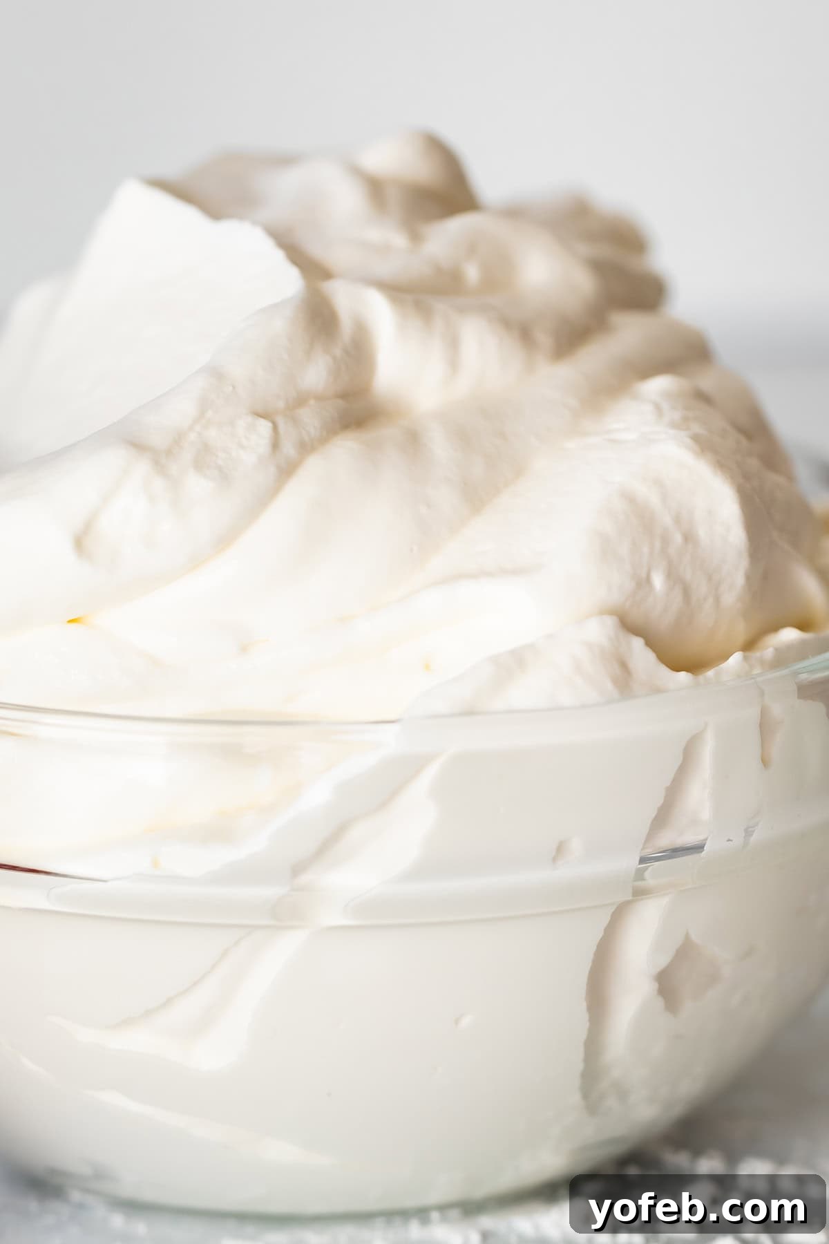 Homemade Whipped Cream Made Easy 3 close up of glass bowl sitting on marble counter, piled high with whipped cream.