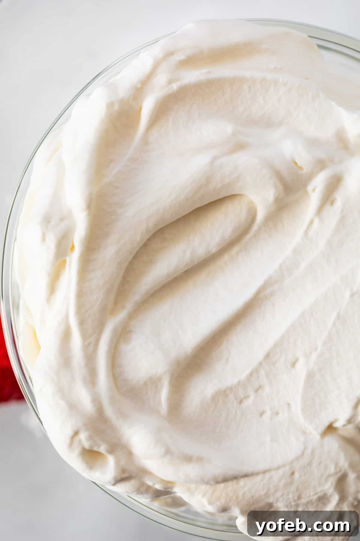 Homemade Whipped Cream Made Easy 5 looking down on a glass bowl of whipped cream with a smoothed top.