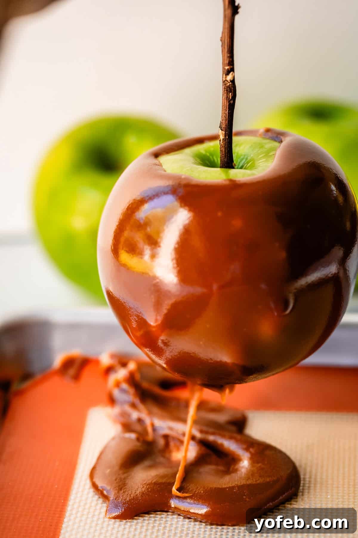 My Ultimate Caramel Apple 29 A caramel apple is gently lifted from the silpat baking mat, revealing excess caramel that pooled at the bottom, which can be scraped and returned to the pot.