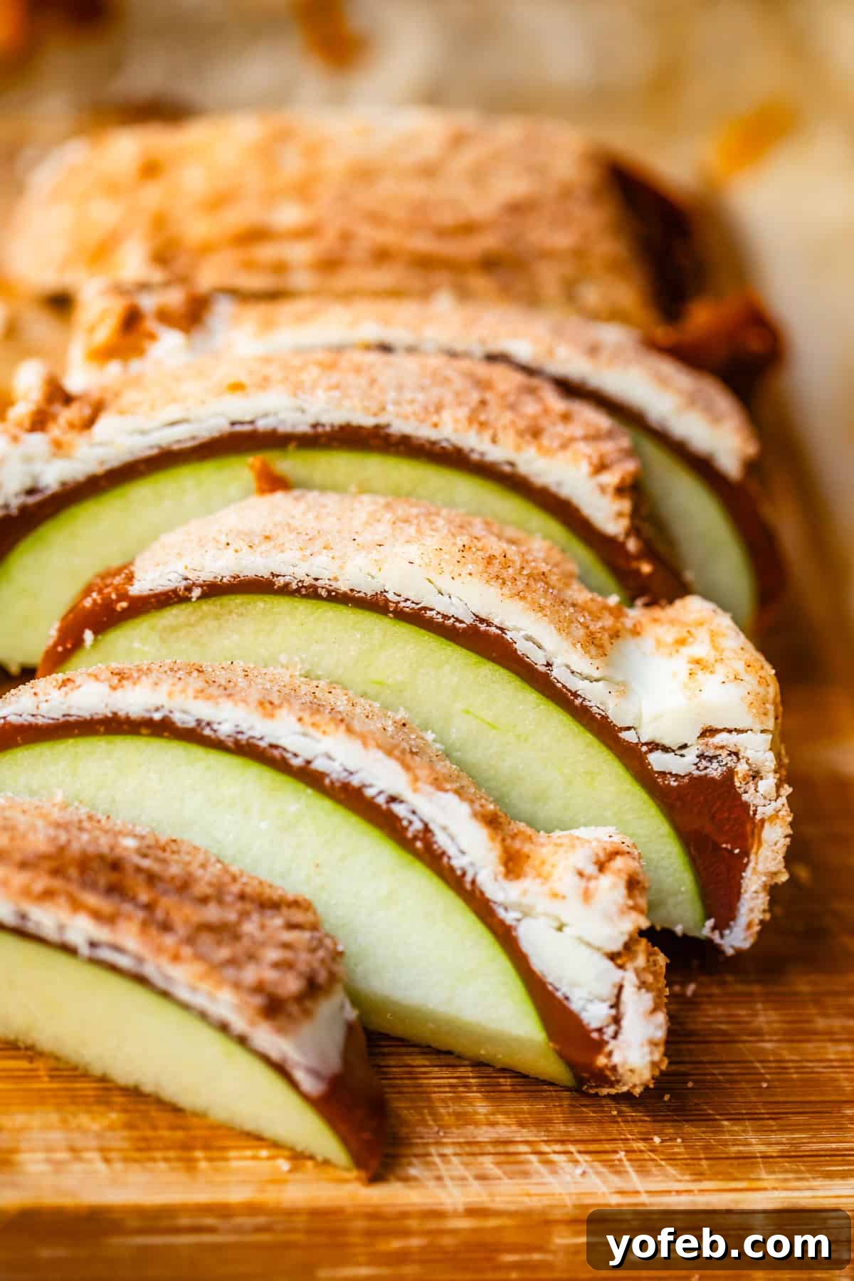 My Ultimate Caramel Apple 32 Close-up of caramel apple slices generously coated in a snickerdoodle topping, arranged invitingly on a rustic wood cutting board.