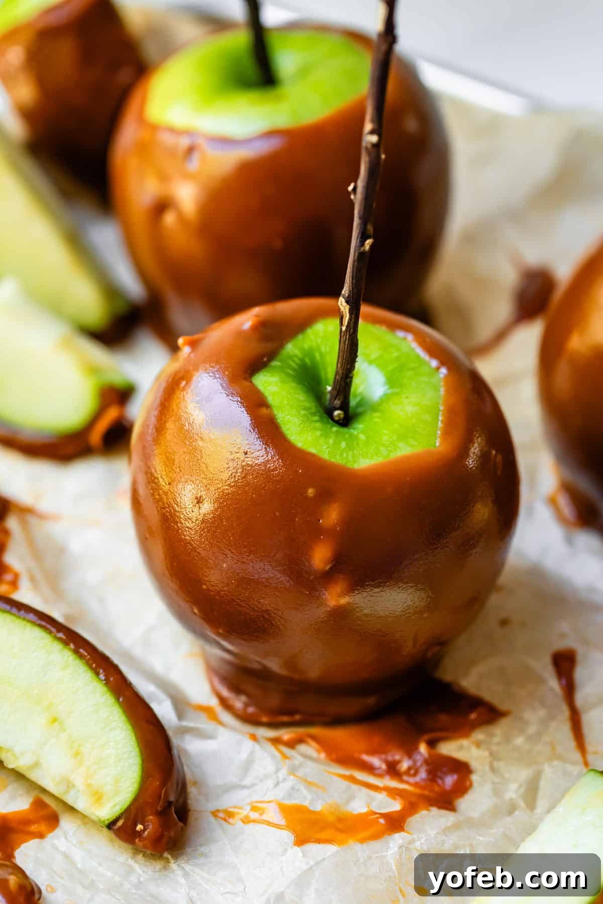 My Ultimate Caramel Apple 33 A vibrant green caramel apple, perfectly coated and ready for a bite, with a sturdy stick in its center, resting on parchment paper.