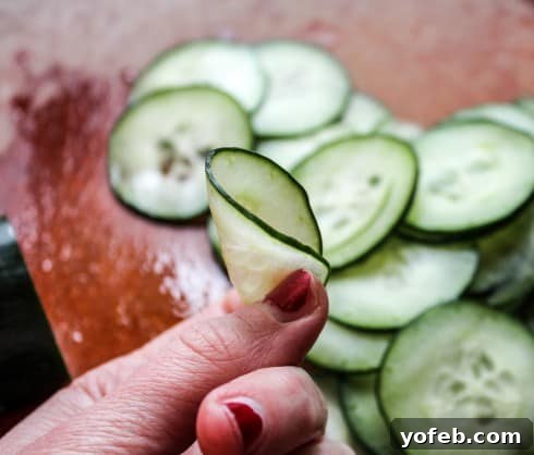 Zesty Mexican Cucumber Salad 2 A hand demonstrating the flexibility of a perfectly thin cucumber slice, indicating ideal thickness for salad.