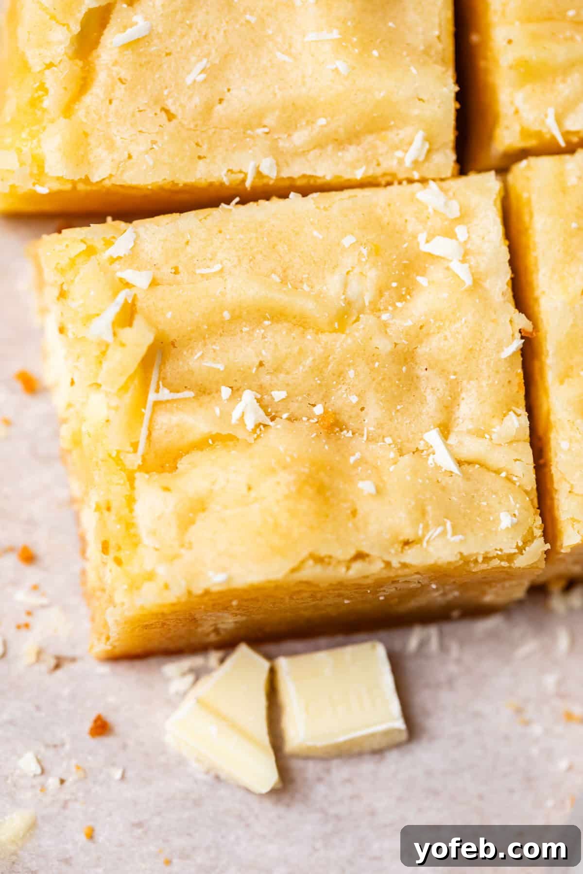 Irresistible White Chocolate Brownies 22 Overhead view of perfectly cut white chocolate brownies arranged in a grid, showcasing their enticing appearance and readiness for serving.
