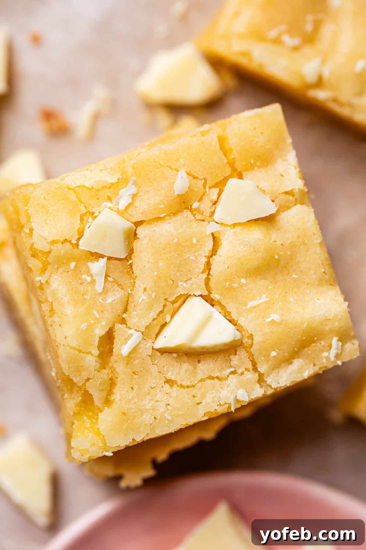 Irresistible White Chocolate Brownies 6 Overhead view of a perfectly cut square piece of fudgy white chocolate brownie, showcasing its dense texture and delicate appearance.