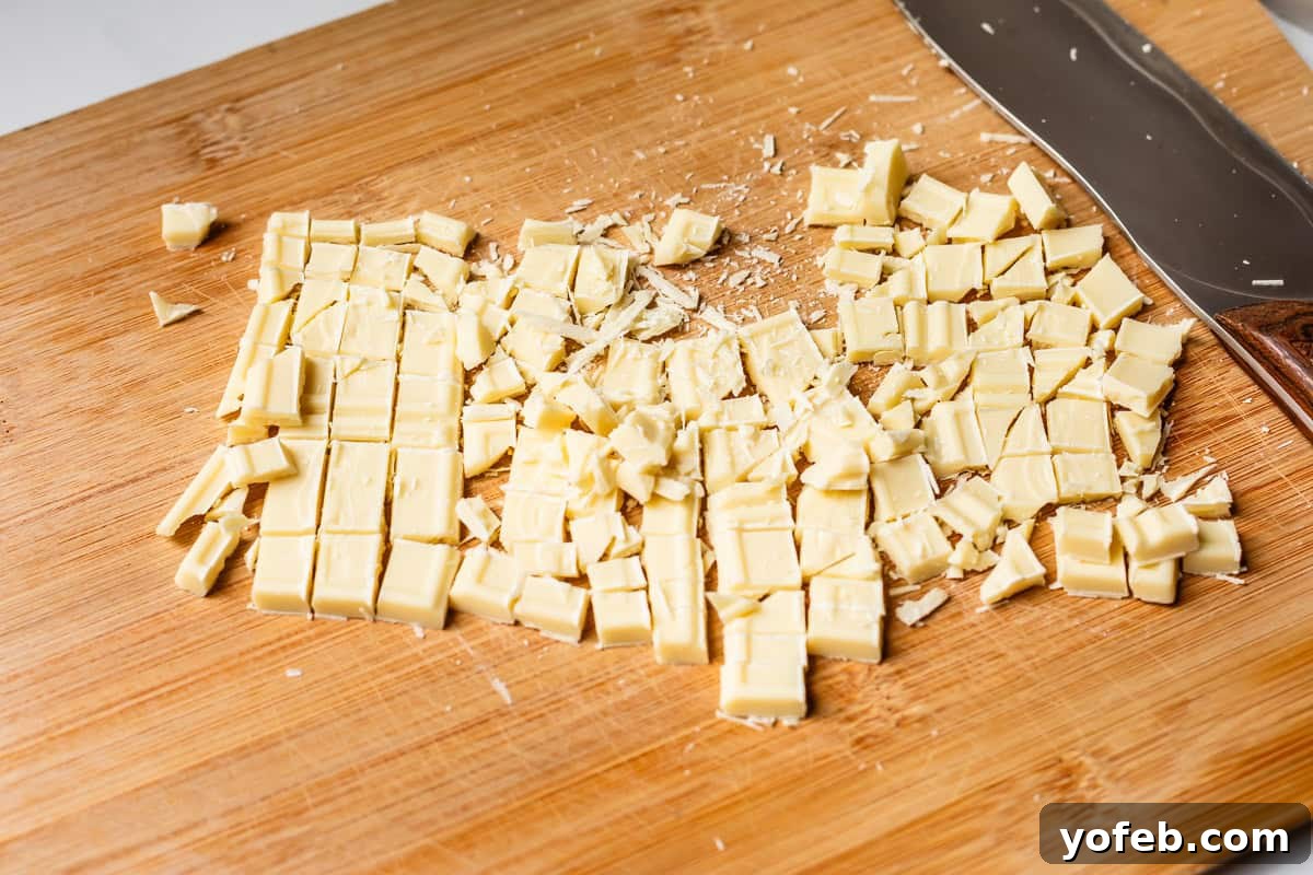 Irresistible White Chocolate Brownies 10 Finely chopped white chocolate on a cutting board, illustrating the preparation of high-quality ingredients for baking.