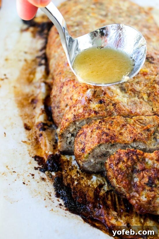 Ina Garten's 1770 House Meatloaf 2 A close-up shot of a baked meatloaf with a generous amount of savory garlic sauce being spooned over its surface, highlighting its rich texture and appealing aroma.
