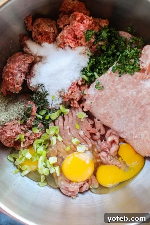 Ina Garten's 1770 House Meatloaf 4 A vibrant mix of ground beef and pork, enhanced with fresh eggs, bright green onions, aromatic herbs, and savory seasonings, ready to be shaped into homemade meatballs or meatloaf.
