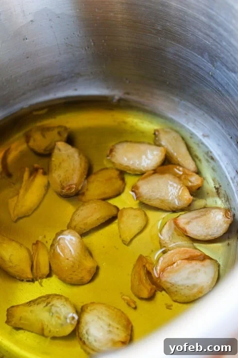 Ina Garten's 1770 House Meatloaf 9 Whole garlic cloves simmering gently in olive oil, creating an aromatic base for the rich garlic sauce that accompanies the meatloaf.