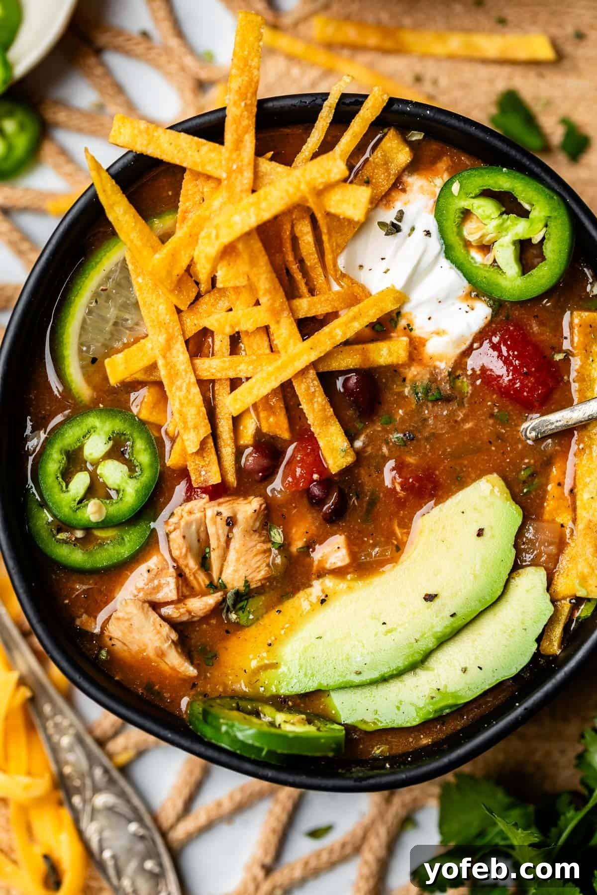 No-Fuss Chicken Tortilla Soup 22 bowl of soup with fried tortilla strips, avocado, and jalapeno.