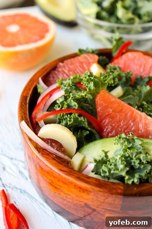 Zesty Avocado & Ruby Grapefruit Medley 4 Vibrant grapefruit and kale salad with hearts of palm in a rustic wooden bowl, ready to be served