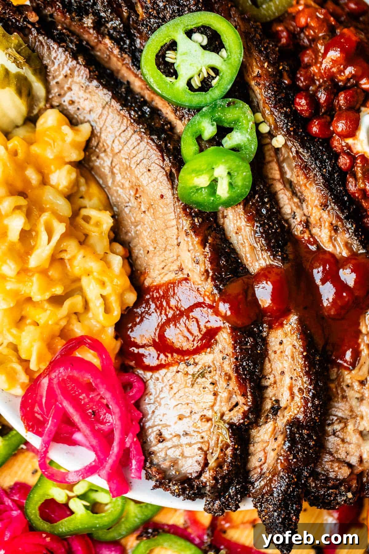 Texas Brisket: Oven-Perfected Tenderness 11 Plate of slices of beef brisket with mac & cheese and beans with bbq sauce.
