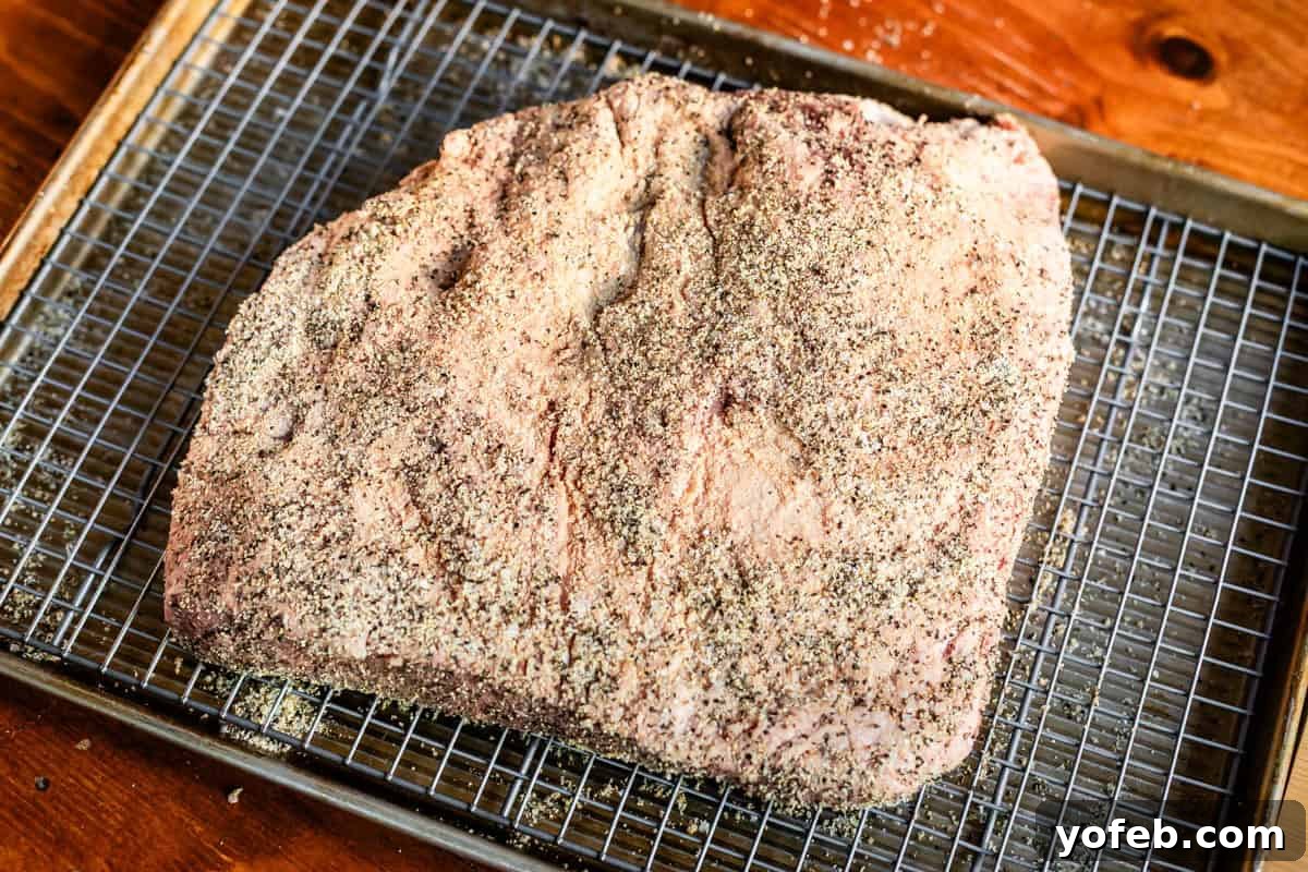 Texas Brisket: Oven-Perfected Tenderness 16 brisket covered in dry brine of salt, pepper, and garlic sitting on a tray on a sheetpan.