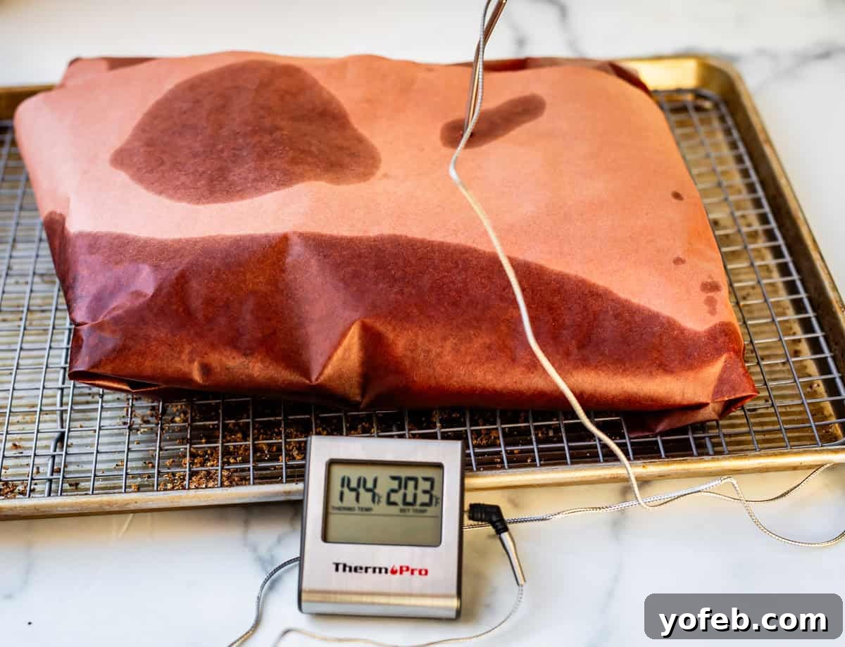 Texas Brisket: Oven-Perfected Tenderness 30 butcher paper wrapped brisket on baking sheet with thermometer reading 203 degrees.