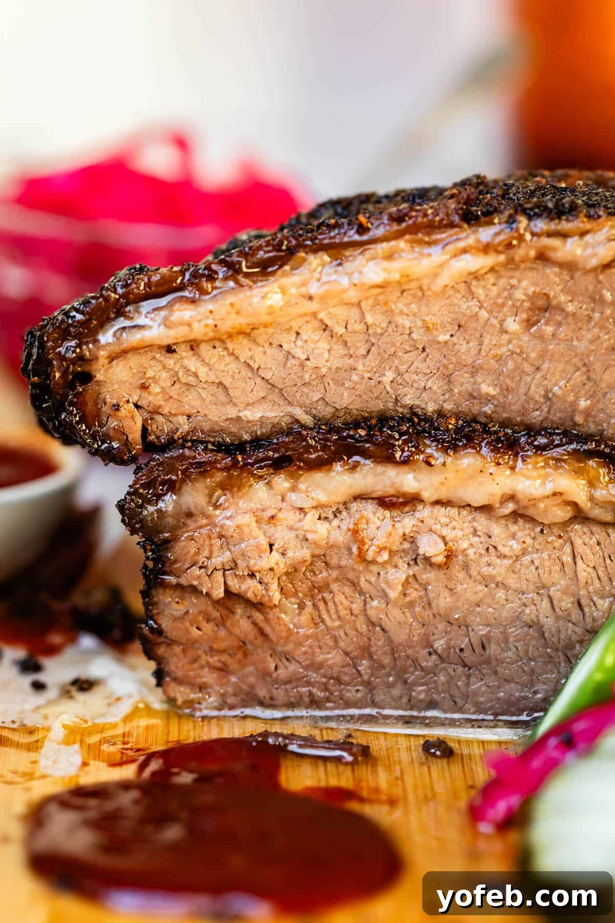 Texas Brisket: Oven-Perfected Tenderness 4 Two cuts of beef brisket stacked together on bamboo cutting board.