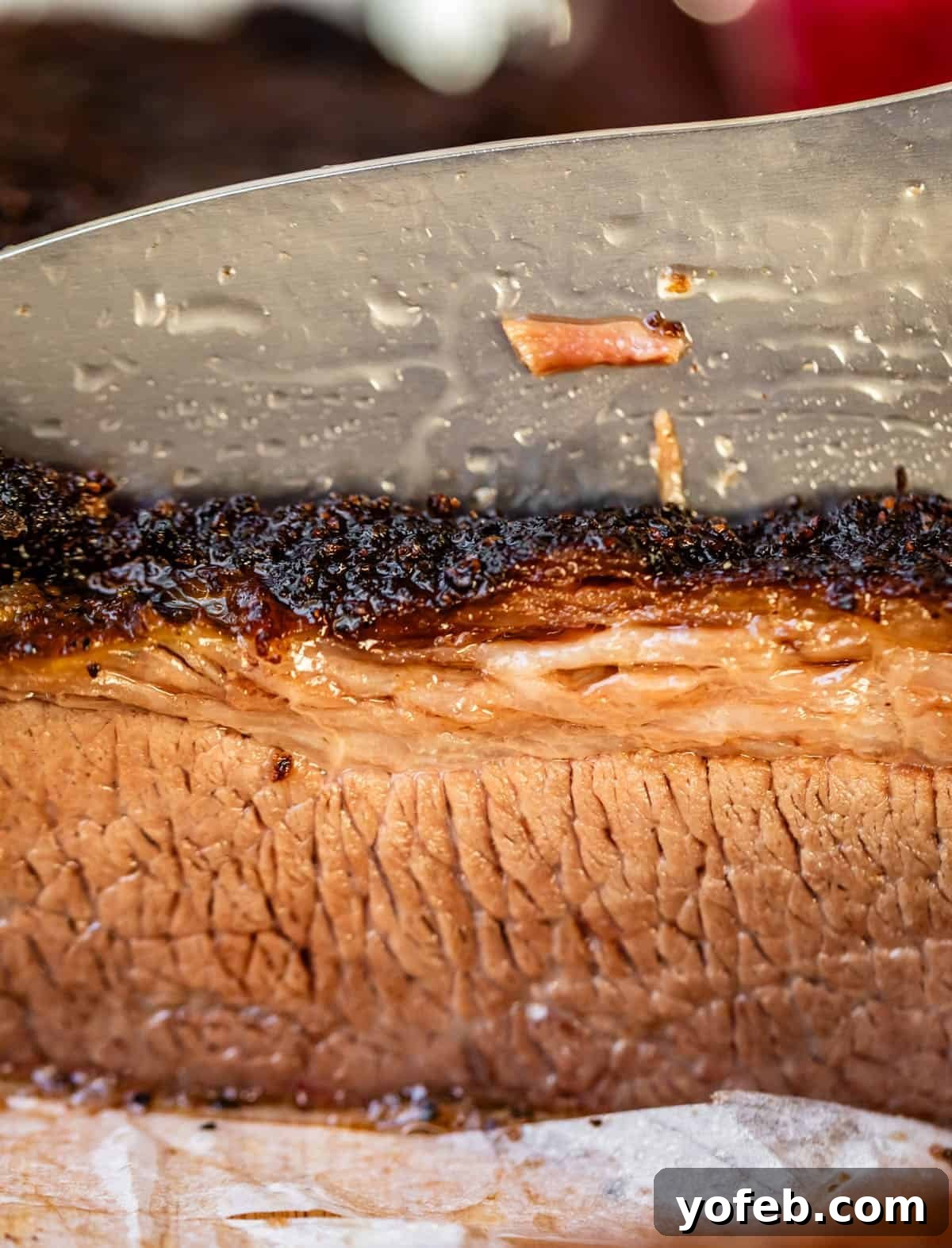Texas Brisket: Oven-Perfected Tenderness 33 knife cutting into brisket to show the smoked bark on top and the cross cut of the grain.