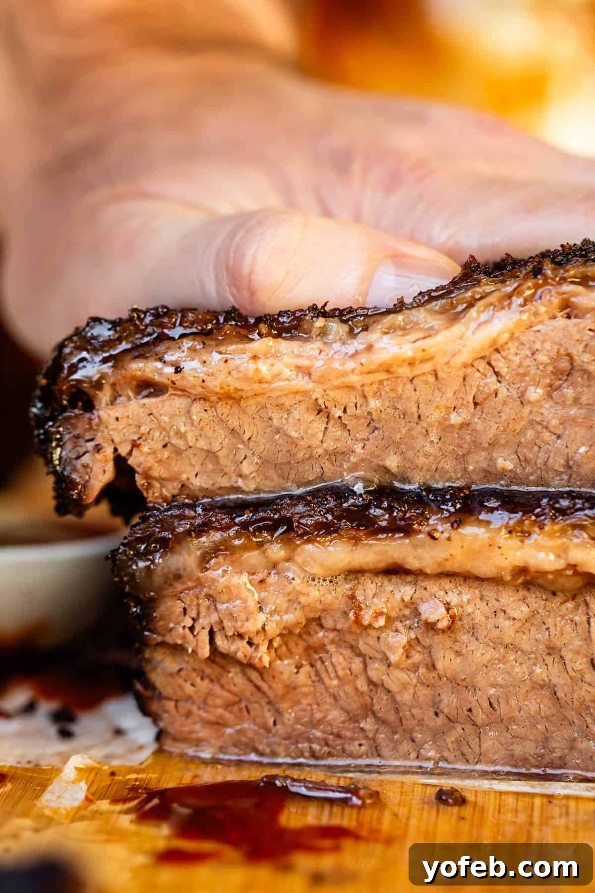 Texas Brisket: Oven-Perfected Tenderness 36 Juicy brisket cross cut stacked on wooden cutting board.
