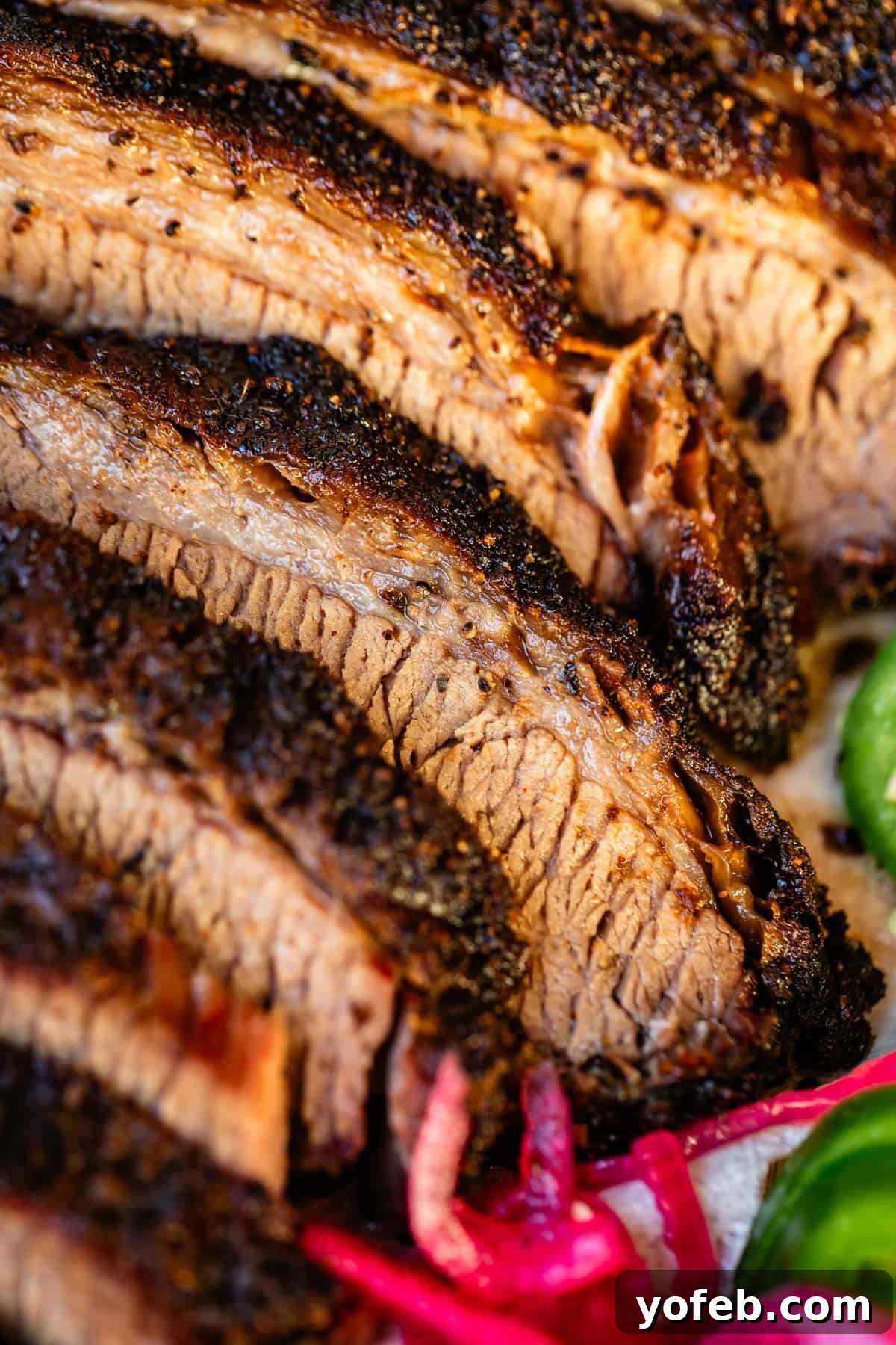 Texas Brisket: Oven-Perfected Tenderness 37 Slices of beautifully charred beef brisket laid out with jalapeño and pickled onions.