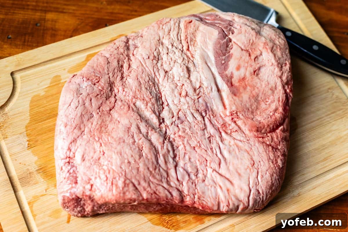 Texas Brisket: Oven-Perfected Tenderness 6 brisket flat sitting on a wooden cutting board with a knife next to it.