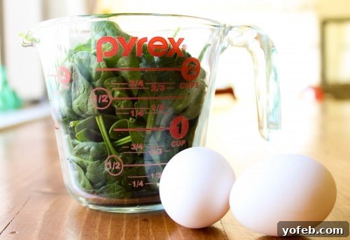 Garden Green Eggs and Ham 4 A measuring cup filled with fresh spinach leaves and two whole eggs, ready for blending.