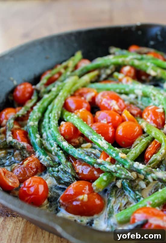 Crisp Asparagus and Tomato Medley 6 Close-up of perfectly cooked asparagus and cherry tomatoes in a black cast iron pan, showcasing their vibrant colors.