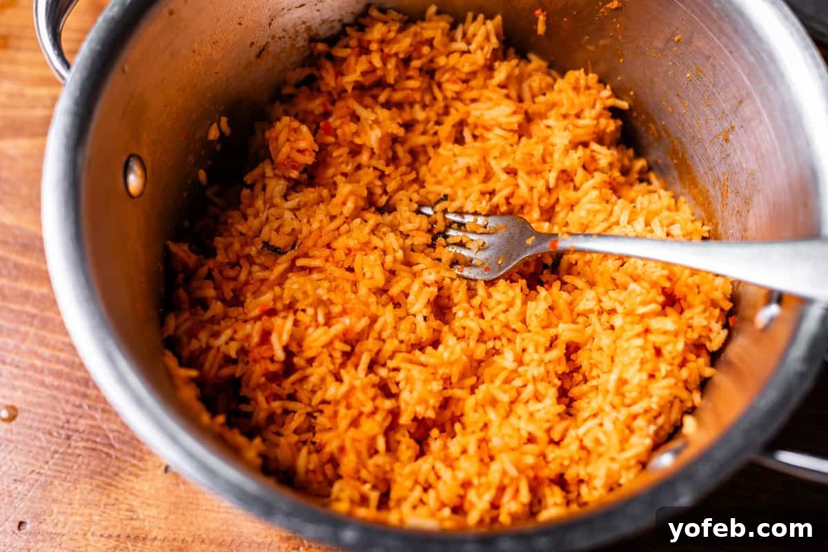 The Ultimate Homemade Mexican Rice 12 fork in metal pot and completely fluffed rice ready to serve.