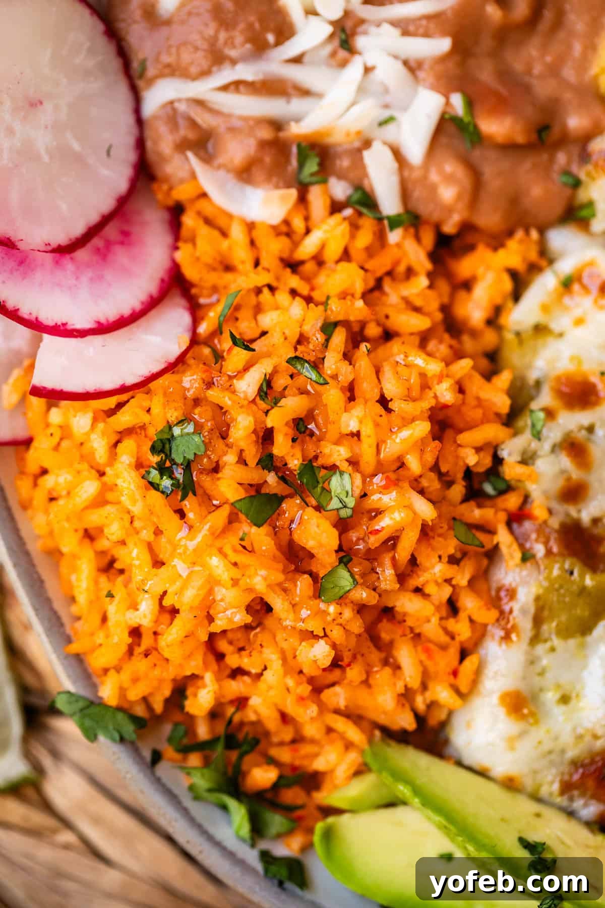 The Ultimate Homemade Mexican Rice 14 close up of the Mexican rice on a plate next to enchiladas and beans.