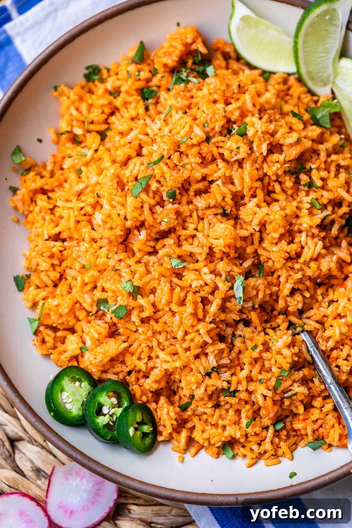 The Ultimate Homemade Mexican Rice 3 a round serving platter filled with Mexican rice and jalapeno, lime, and cilantro garnish.