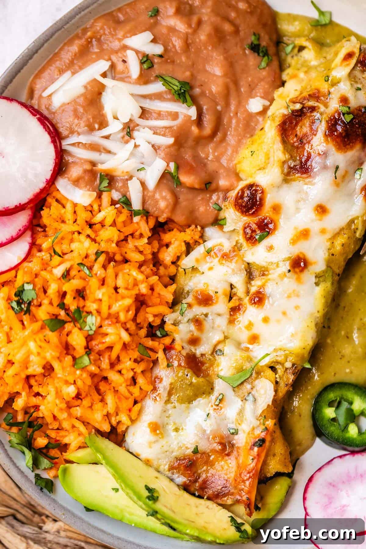 The Ultimate Homemade Mexican Rice 4 plate filled with salsa verde enchiladas, refried beans, and Mexican rice.