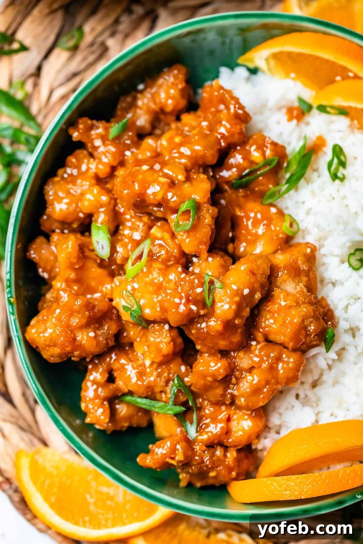 Ultimate Orange Chicken 5 Close up of a vibrant ceramic bowl showcasing golden, crispy orange chicken, generously garnished with fresh green onions, ready for serving.