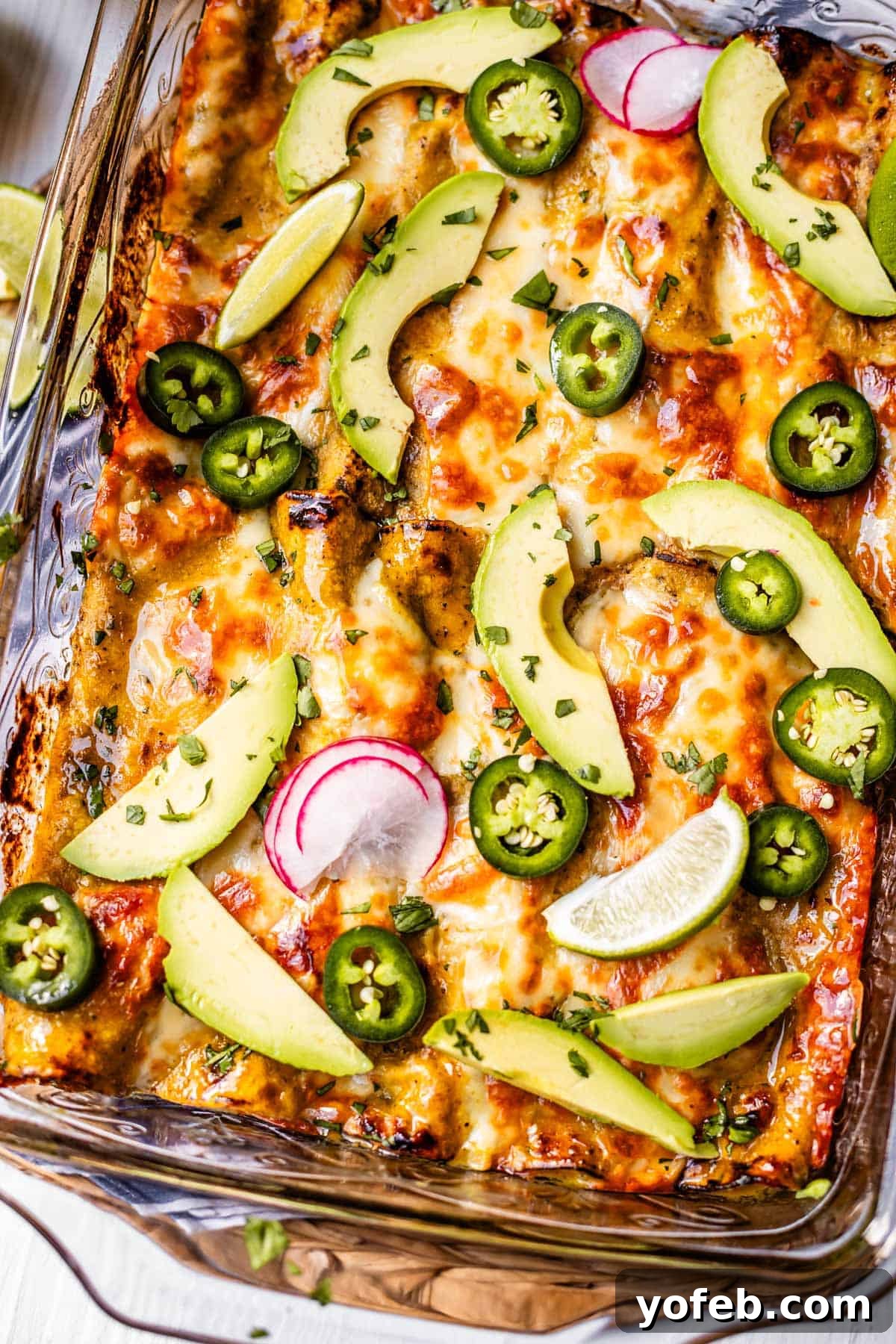 Yeni Gözdem Tavuk Enchilada 24 looking down at a glass casserole dish of baked enchiladas, topped with avocado, radish, jalapeno, etc.