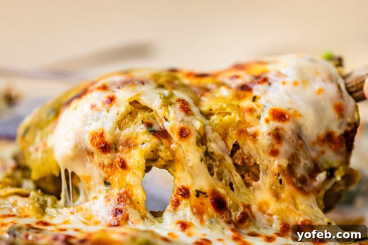 Yeni Gözdem Tavuk Enchilada 5 metal spatula lifting up an enchilada to serve showing all the delicious cheese stretch.
