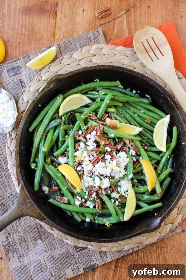 Zesty Green Beans with Creamy Feta and Crispy Pecans 3 Close-up of vibrant green beans topped with white feta cheese and golden fried pecans in a serving bowl.