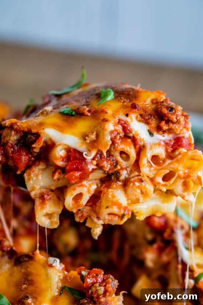 Perfectly Melted, Stretchy Cheese in Baked Ziti. A piece of baked ziti being lifted, showing delicious stretchy melted cheese.