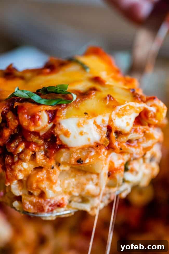 Cheesy Baked Ziti Slice, Ready to Enjoy. A serving spoon lifts a perfect slice of baked ziti, showing off the melted cheese and pasta layers.