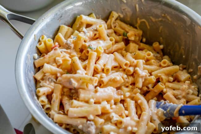 Combining Pasta with Creamy Cottage Cheese Mixture. Mixing the creamy ricotta (cottage cheese) mixture with cooked pasta in a large pot.