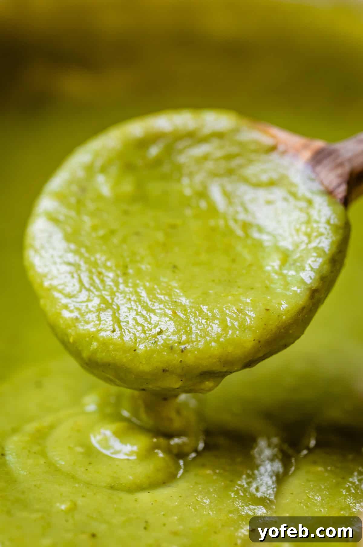 Tangy Tomatillo Enchilada Sauce 16 a wooden spoon pouring some green enchilada sauce back into more sauce.