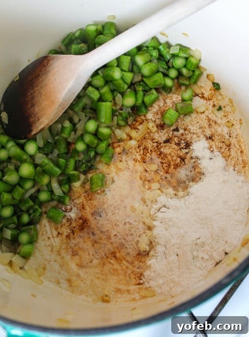 Vibrant Spring Asparagus Puree 8 Making a roux in a pot, with sautéed asparagus pushed to one side, demonstrating a practical cooking method.