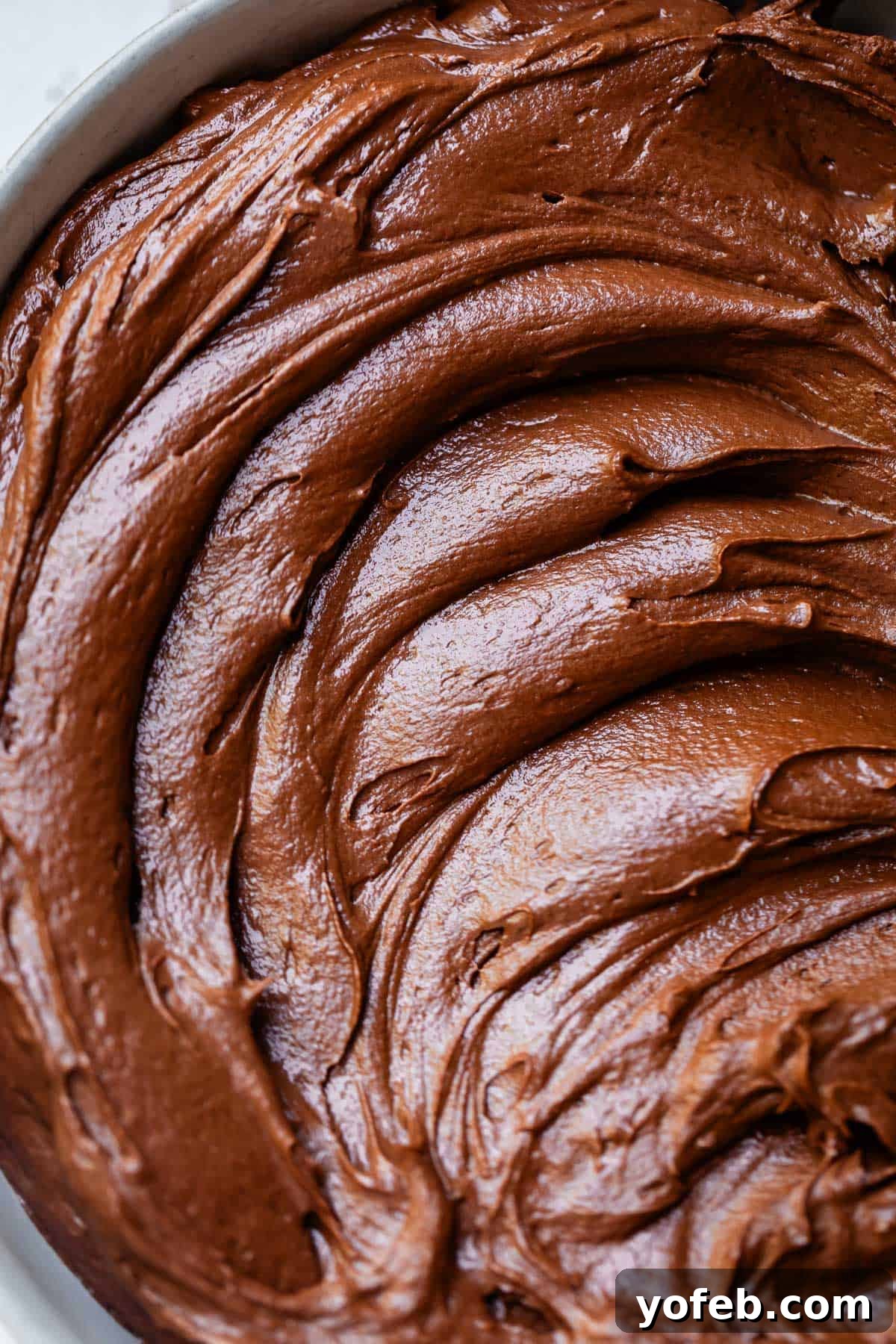 Luscious Chocolate Buttercream: Spoon-Licking Guaranteed 17 overhead shot looking down at swirled, creamy chocolate buttercream frosting in a bowl.