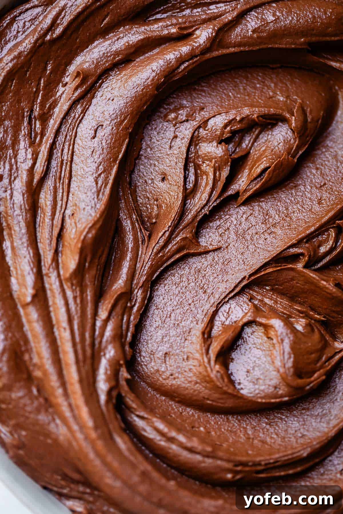 Luscious Chocolate Buttercream: Spoon-Licking Guaranteed 4 overhead shot looking down at swirled, creamy chocolate buttercream frosting in a bowl.