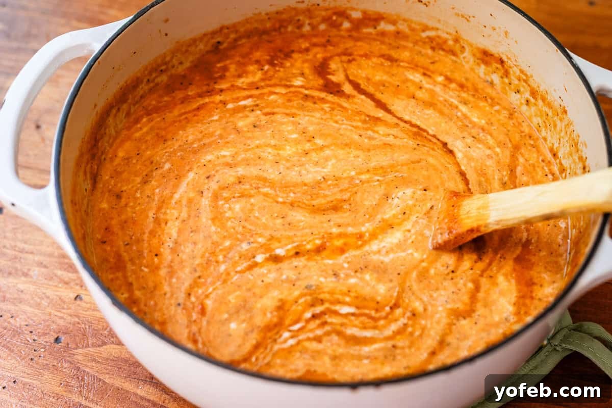 Laura's Sumptuous Tomato Bisque 14 A vibrant tomato bisque, with the creamy white sauce just beginning to mix in, highlighting its velvety smooth texture.